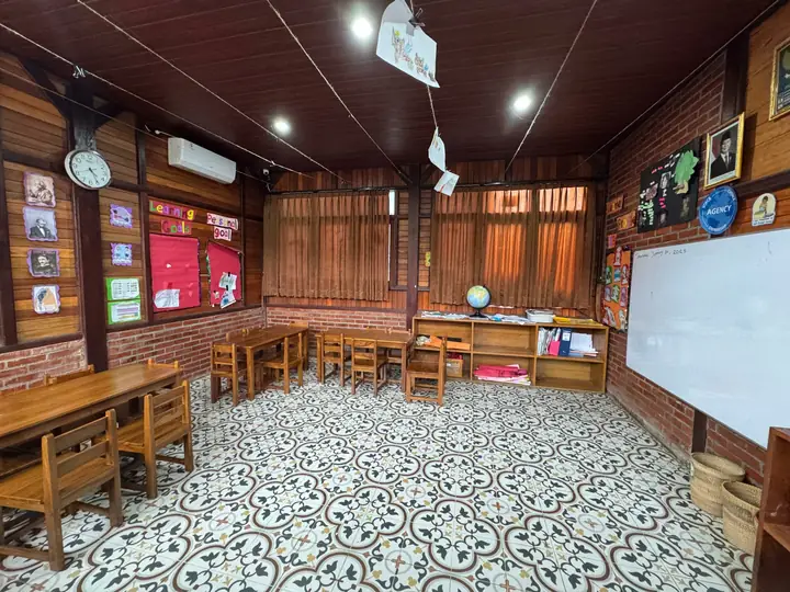Bright wooden classroom with small desks, a whiteboard and patterned tiles