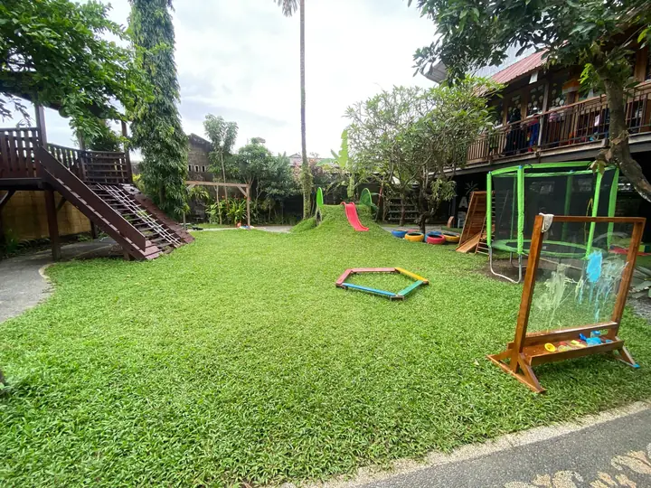 Garden playground with a wooden climbing frame and an outdoor easel