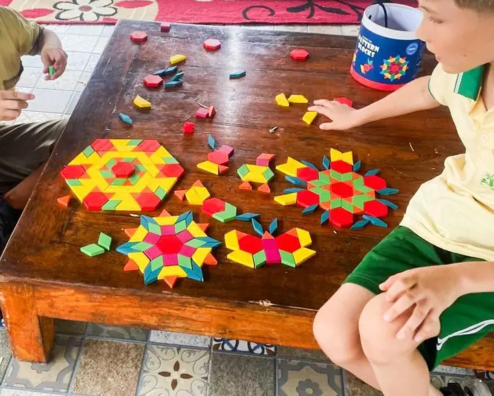 Colourful pattern blocks arranged into stars on a wooden table