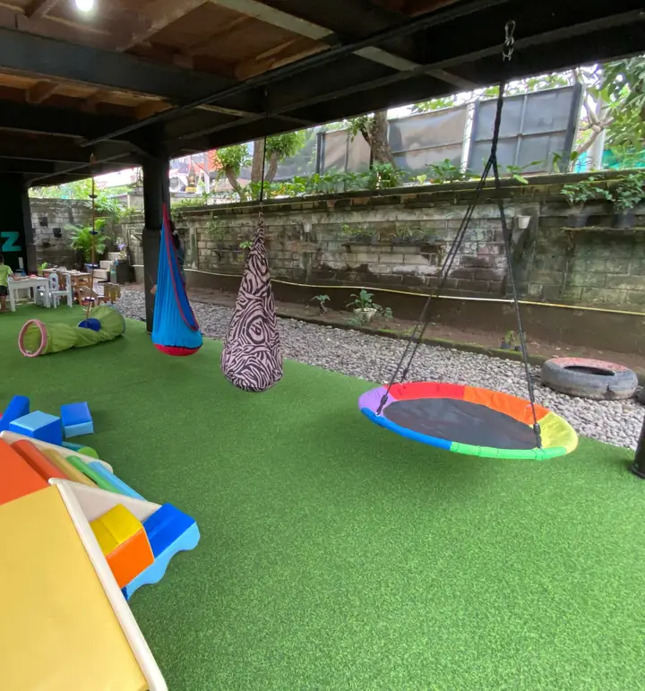 Indoor play space with soft climbing blocks, a slide and a nest swing